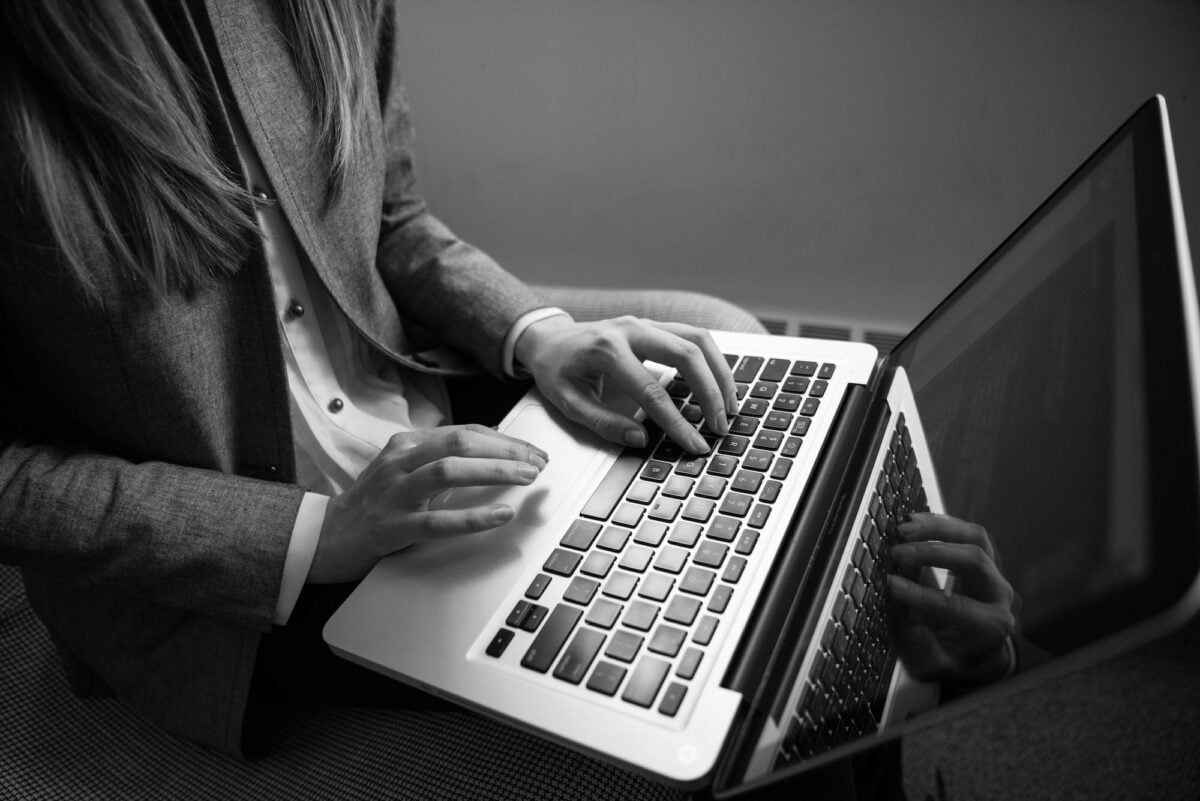 grayscale photography of woman typing on a laptop